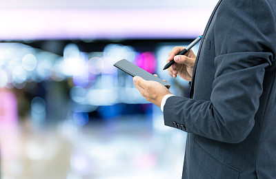 孤立的商人拿着智能手机在商场背景上图片下载