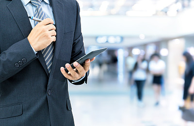 孤立的商人拿着智能手机在商场背景上图片下载