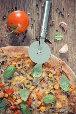 复古照片，披萨切割机与素食披萨，配料和香料在木板上图片下载