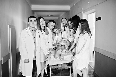 在医院里，滑稽的医生在病床上为病人摆姿势。黑白照片。图片下载