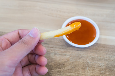 手指拿着炸薯条蘸番茄酱图片下载