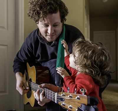 微笑的吉他手和着迷的幼童图片下载