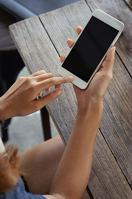 年轻女子坐在桌边用手机端着咖啡。图片下载