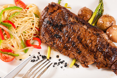 烤牛排配芦笋，意大利面，黑岩盐图片下载