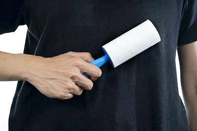 一名妇女用粘胶滚筒去除衣服上的猫和狗毛，图片下载