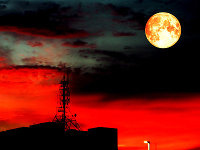 超级饱满的血月和模糊的阴影信号柱在屋顶上图片下载