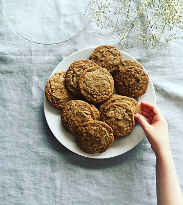 孩子的手臂从盘子里抓了一块饼干。图片下载