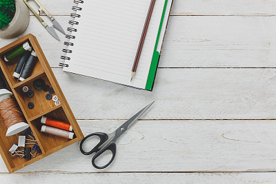 俯视图配件裁缝概念。裁剪工具包括剪剪刀、线轴、纽扣和缝纫衣服。笔记本为自由空间文本在乡村木制背景。时尚的概念。平的。图片下载