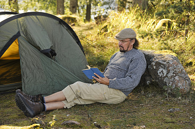 一位老人坐在帐篷外看书图片下载