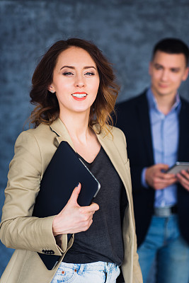 一个快乐的女人拿着笔记本看着相机。图片下载