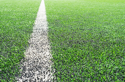 从俯视图看，绿色足球场的人造草坪表面有白色的角线作为背景图片下载