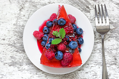 美味的芝士蛋糕，新鲜的浆果和薄荷，用叉子放在盘子里图片下载