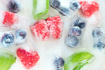 树莓，蓝莓和薄荷叶的冰块在白色的背景素材图片
