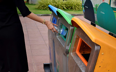 女人们把空瓶子扔到垃圾桶里。素材图片