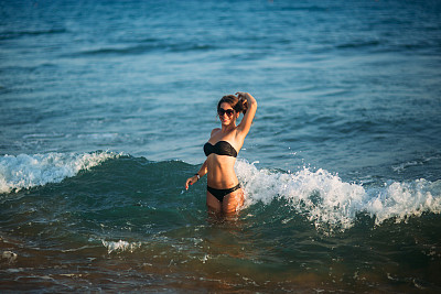 性感的女孩在沙滩上晒太阳，坐在海边图片下载