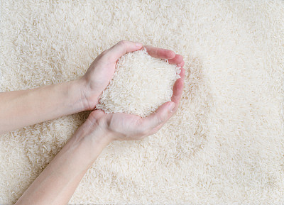 女手铲生白茉莉米纹理图案背景，新软米粒生长在泰国(东南亚国家)很好的烹饪亚洲菜素材图片