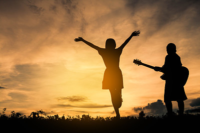 剪影男孩和女孩正在享受演奏音乐。图片下载