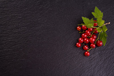 新鲜的红加仑子在黑色石板的背景。图片下载