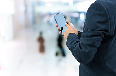 孤立的商人拿着智能手机在商场背景上图片下载