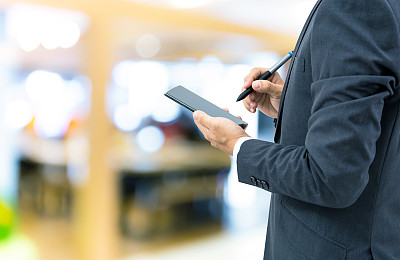 孤立的商人拿着智能手机在商场背景上图片下载