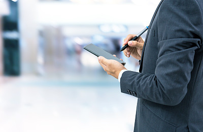 孤立的商人拿着智能手机在商场背景上图片下载