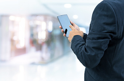 孤立的商人拿着智能手机在商场背景上图片下载