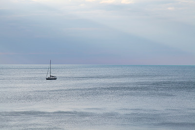 游艇在海上从云中照射出的风景图片下载