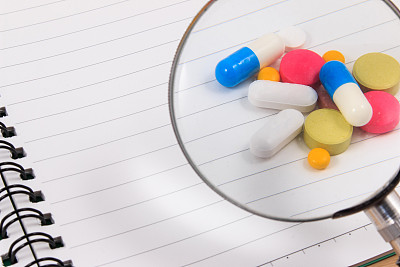 放大和许多彩色药丸在空白记事本上。图片下载