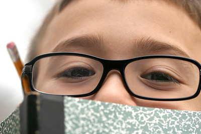 戴眼镜的年轻学生在笔记本上做作业图片下载