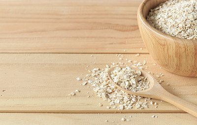 健康食品的概念。旧桌子上的木碗里的燕麦片，背景光线过亮图片下载