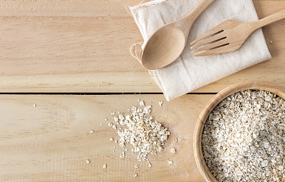 健康食品的概念。旧桌子上的木碗里的燕麦片，背景光线过亮。俯视图图片下载