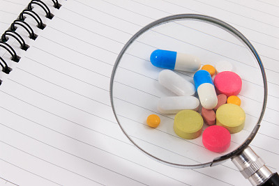 放大和许多彩色药丸在空白记事本上。图片下载