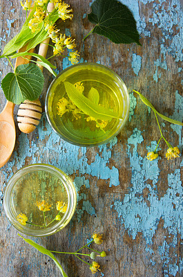 蓝木桌上放着椴树茶和椴树花。一杯健康草药茶和一罐菩提树蜂蜜。带拷贝空间的照片图片下载