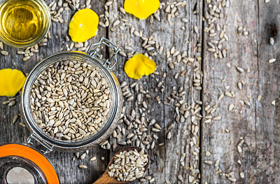 木桌上放着一瓶从葵花籽中提取的油，上面是平放的素材图片