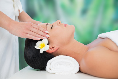 漂亮的黑发女子正在享受头部按摩素材图片