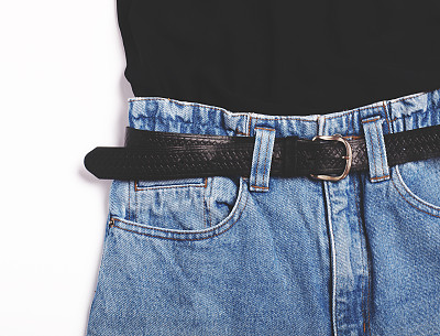 蓝色复古高腰妈妈牛仔裤与黑色腰带和黑色顶部孤立在白色背景的特写。平的。前视图。图片下载