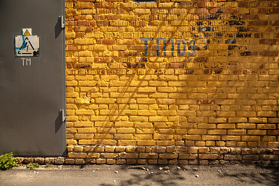 充满活力的黄色砖墙背景与一扇门和一个高压危险标志图片下载