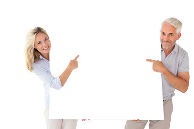 一对幸福的夫妇拿着并指着一张大海报图片下载