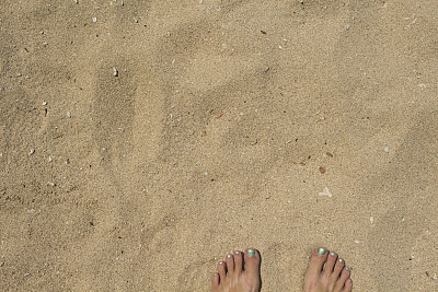 女人的脚在温暖的白沙上。黄色沙滩俯视图照片图片下载