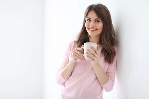 白色背景上拿着一杯咖啡大笑的美丽女人图片下载