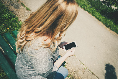 一个迷人的女人在城市街道上走路的时候和某人用手机聊天的半身像。图片下载