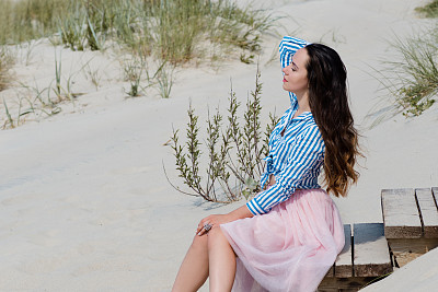 美丽又时尚的黑发姑娘在海滩上散步。坐在楼梯上图片下载