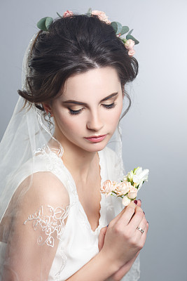 美丽的肖像美丽天真的新娘与面纱孤立在灰色的背景。婚礼的妆容和发型。图片下载