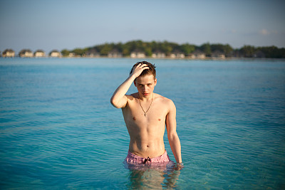 性感的男人在蓝色的海水摆姿势的照片。在海上穿着泳衣的帅哥图片下载