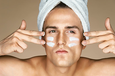 严肃的男人脸上涂了保湿霜。图片下载