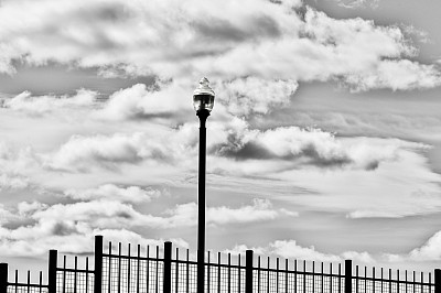 街灯和栅栏映衬着多云的天空图片下载