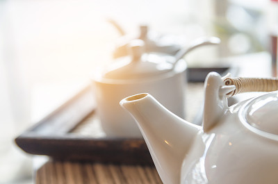 木桌上的白瓷茶壶和绿茶杯，复古色调素材图片