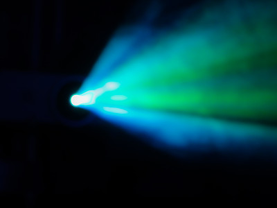 蓝绿色的光线透过投影仪的烟雾。照明设备。表演、音乐会或夜总会。这图像的焦距不对。散景图片下载