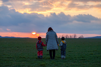 两个可爱的孩子，男孩兄弟，看着美丽的日落在绿色的田野图片下载