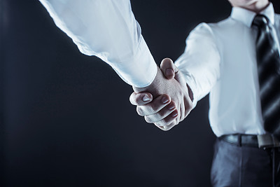 一个可靠的伙伴关系的概念:一个商业伙伴握手的特写在一个黑色的背景图片下载
